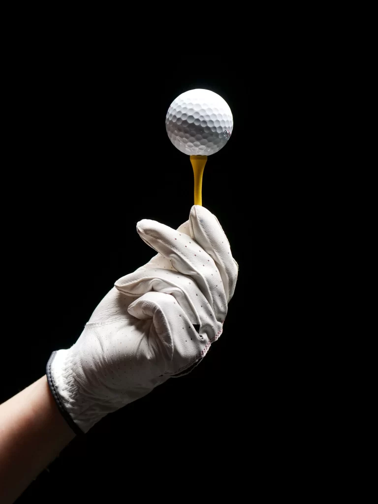 Man Holding Golf Tee which is holding Golf ball