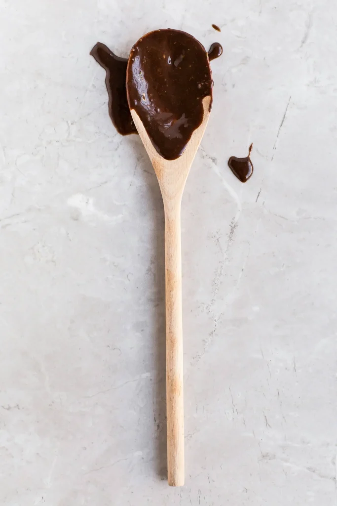 A Long Wooden Kitchen Spatula covered in Chocolate